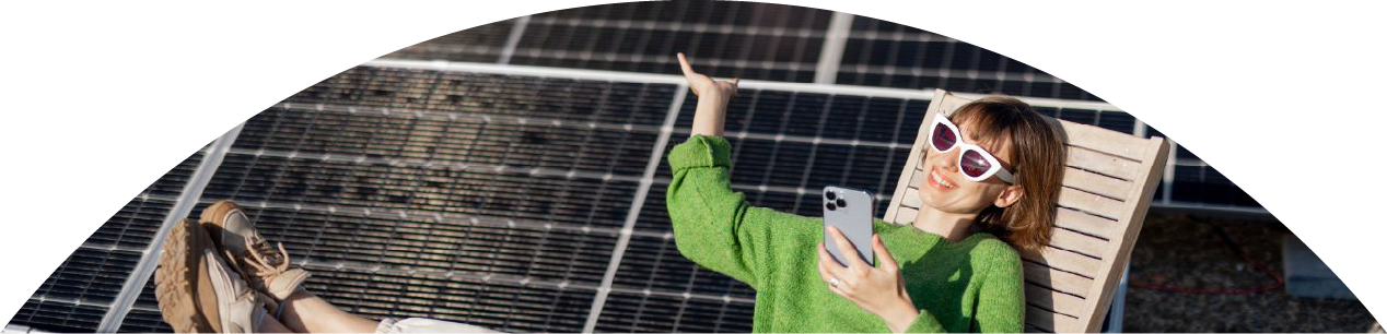 Frau sitzt mit Handy vor Solaranlage